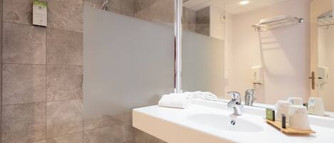 Un baño moderno con un espejo grande, un lavabo y una ducha.