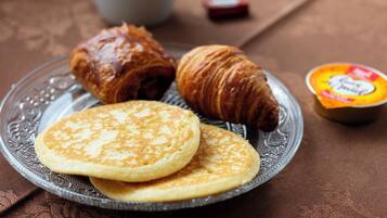 Een bord met pannenkoeken en een croissant op een glazen schotel.