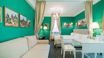 A hotel room with a green wall, two beds, a white sofa, a desk, and a chair.