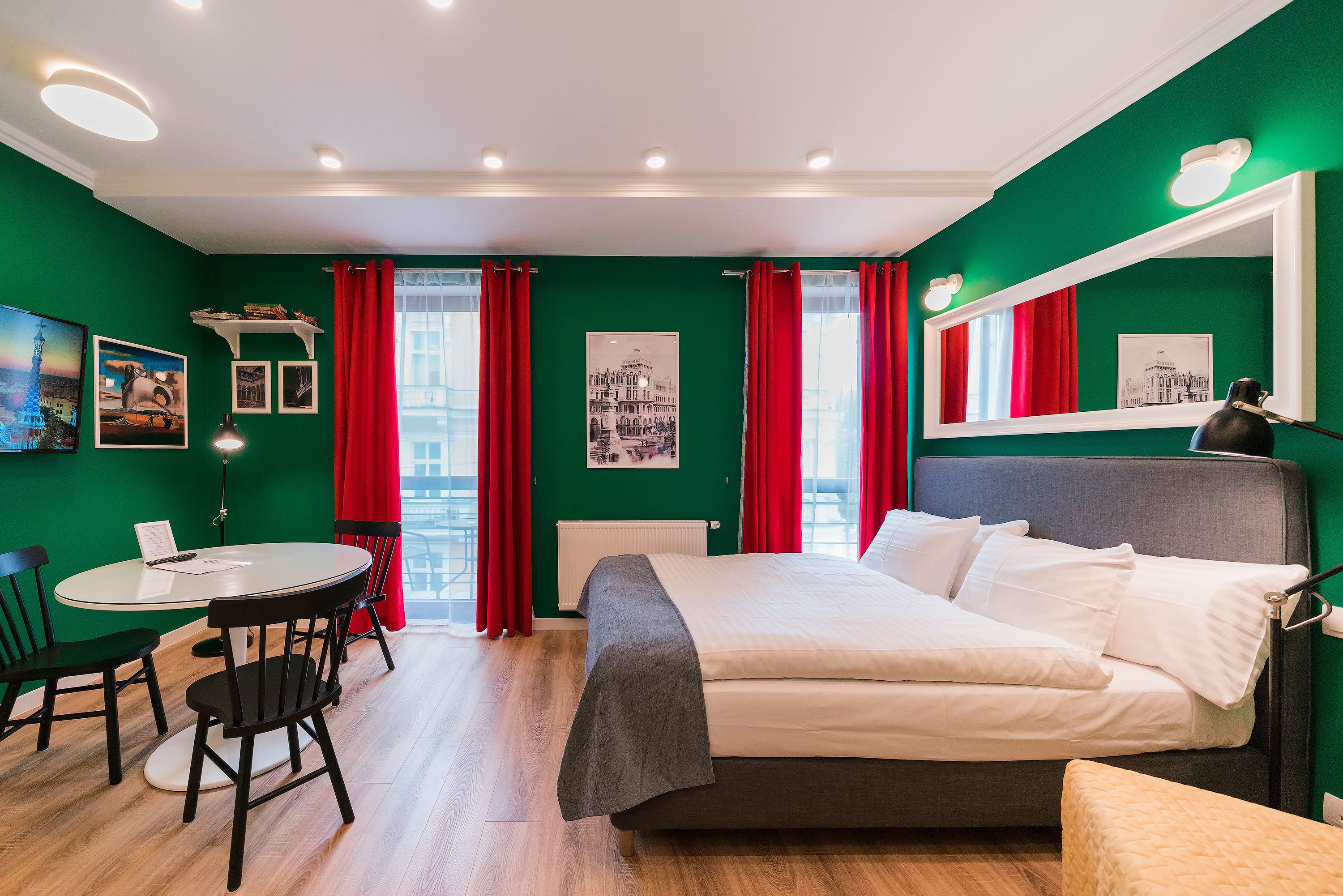 Een hotelkamer met een bed, een bureau, stoelen en een raam met rode gordijnen.