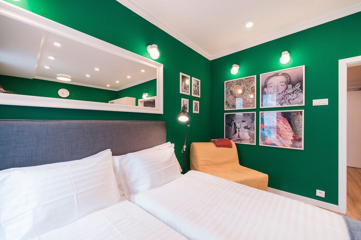 Ein Schlafzimmer mit Bett, Sessel, Nachttisch und Wandbildern.