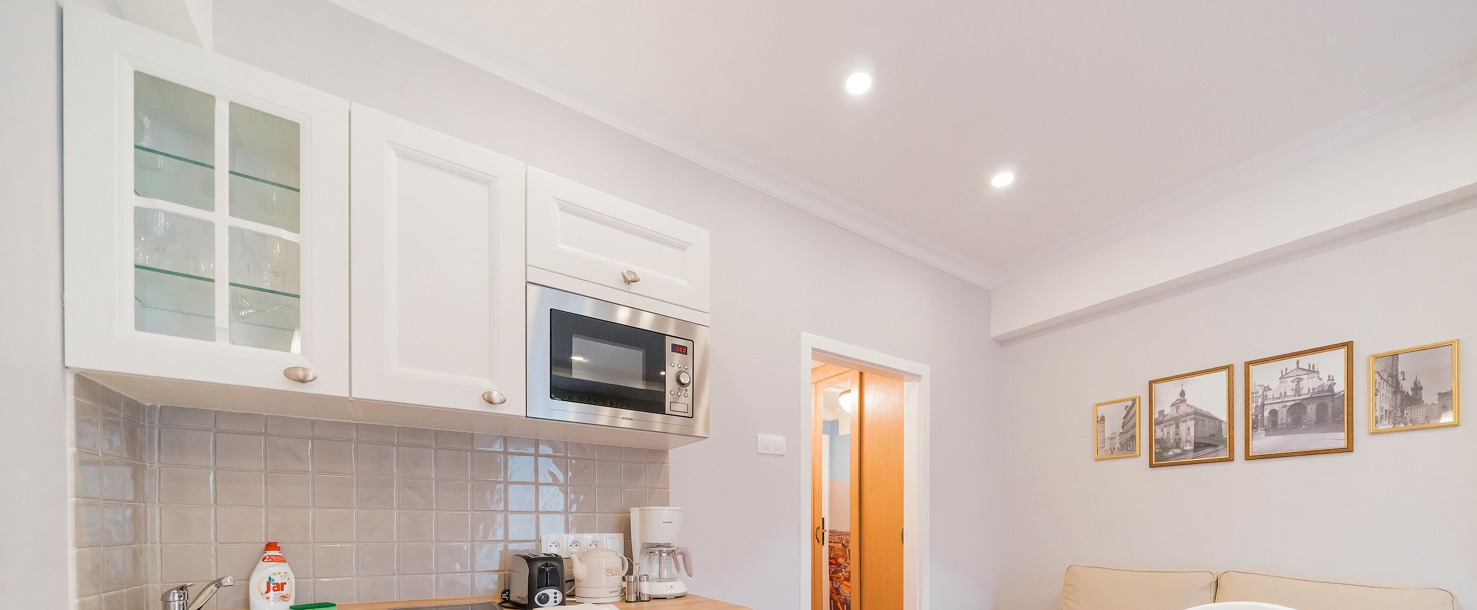 A modern kitchen with white cabinets, a microwave, and a coffee maker.