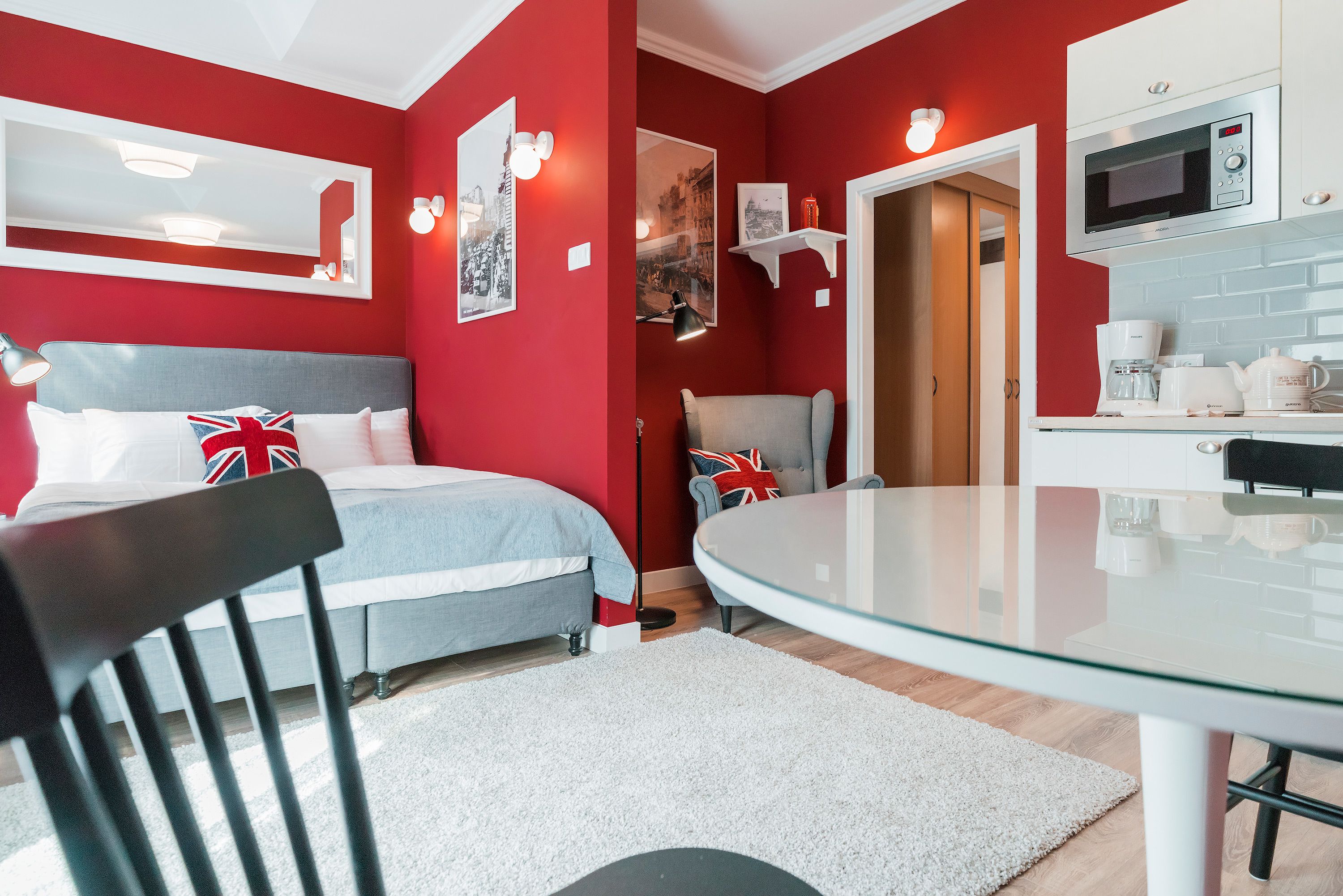 A modern room with a bed, a glass dining table, and a kitchen area.