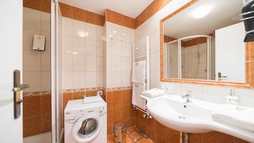 Une salle de bain équipée d’un lave-linge, d’un lavabo et d’un miroir.