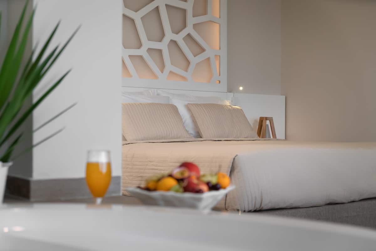 A modern bedroom with a bed, a bedside table with a fruit bowl and a glass of orange juice, and a decorative wall panel.