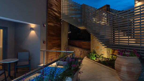 A modern outdoor patio with a pool, seating area, and decorative plants. - KB Ammos (Skiathos)