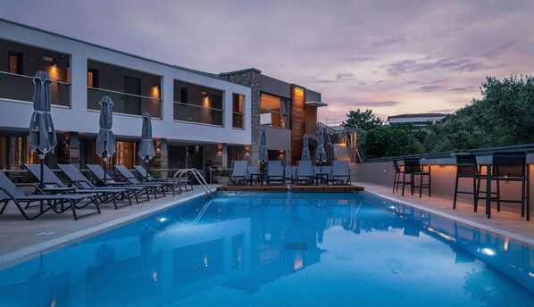 A modern hotel with a swimming pool, sun loungers, and outdoor seating. - KB Ammos (Skiathos)