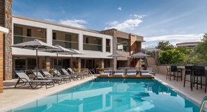 A modern hotel with a swimming pool, sun loungers, and outdoor seating. - KB Ammos (Skiathos)