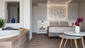 A modern bedroom with a large bed, bedside table, and a small round table with a vase of flowers. - KB Ammos (Skiathos)