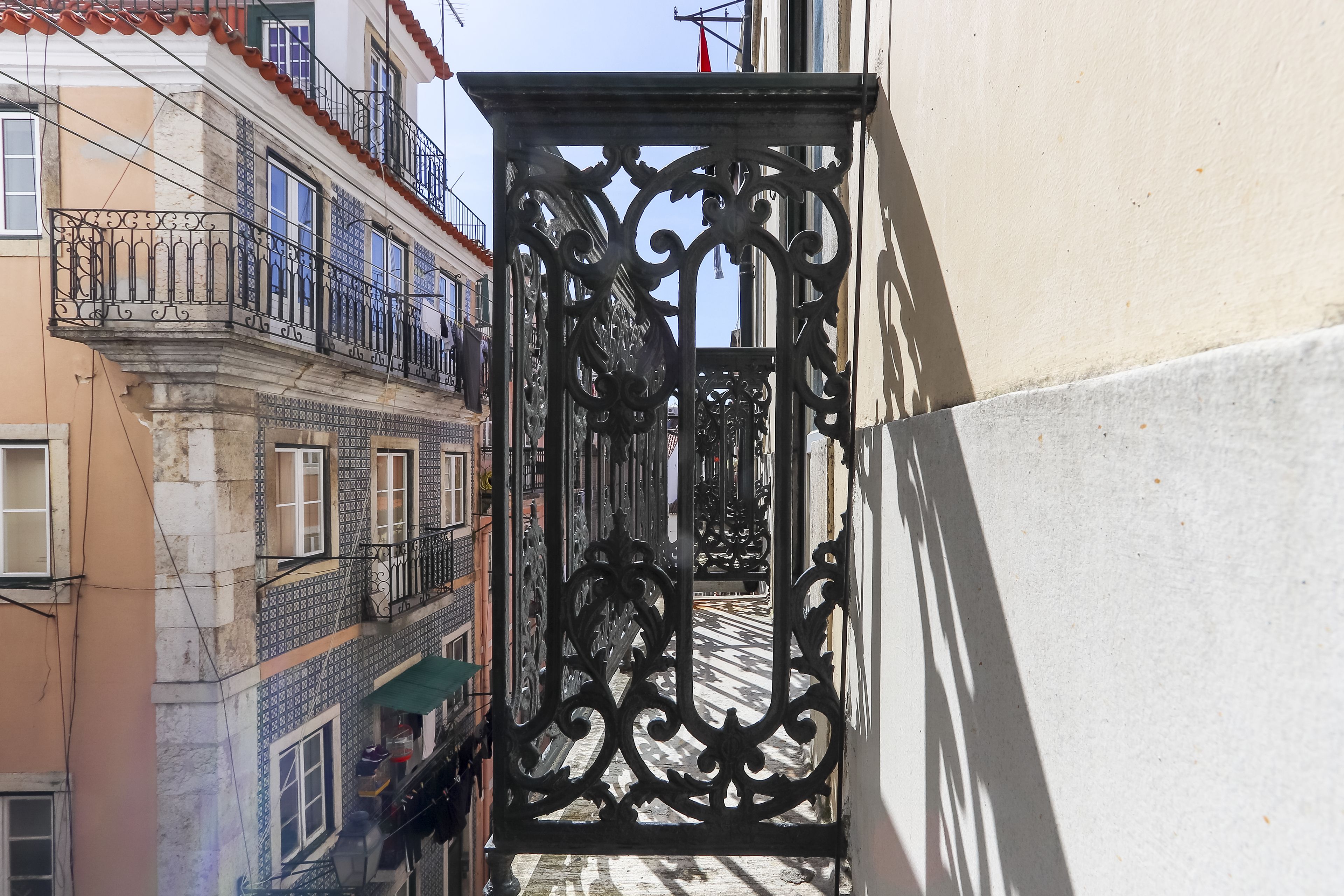 Un estrecho callejón con elaboradas puertas de hierro forjado y pavimento de baldosas.
