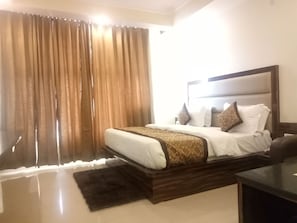 A hotel room with a large bed, a headboard, and a small desk. - Hotel Nek (Reasi)