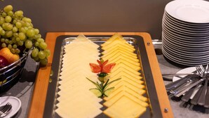 A buffet setup with sliced cheese, fruits, and vegetables. - SKY Hotel Prague (Prague)