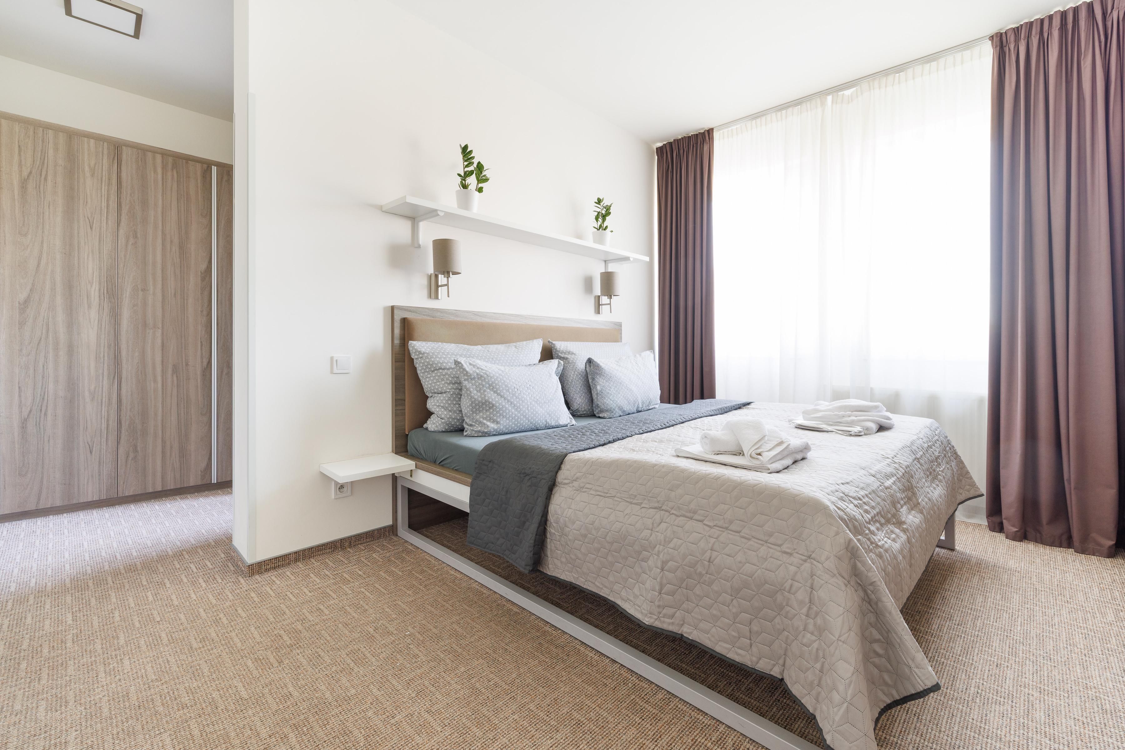 Une chambre à coucher moderne, avec un lit, des tables de chevet et une fenêtre avec des rideaux.