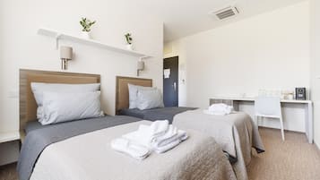 A hotel room with two beds, a desk, and a chair.