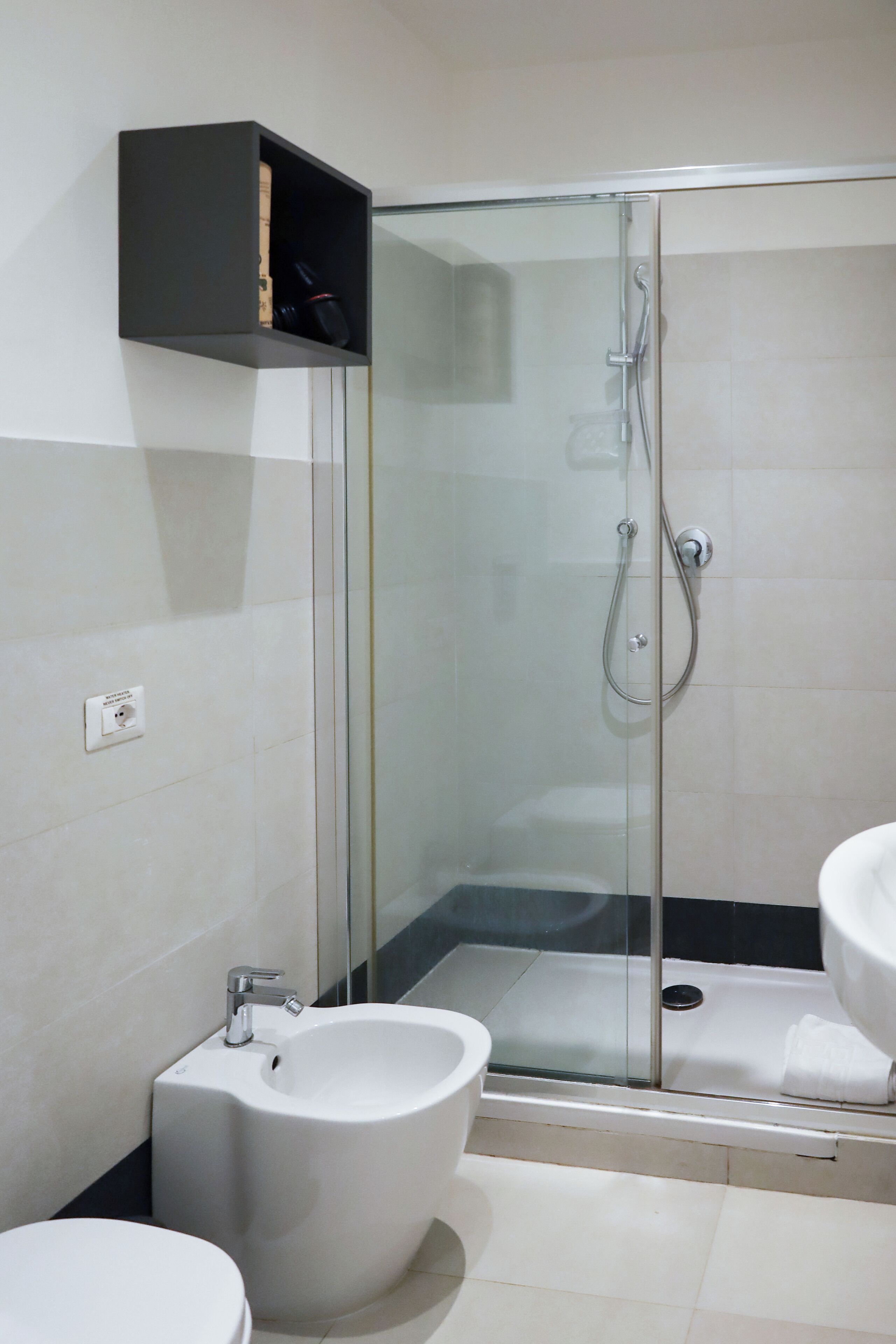 A modern bathroom with a glass-enclosed shower, a bidet, and a sink.