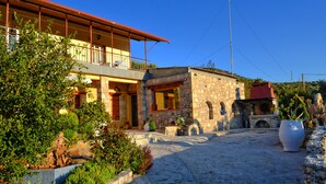 A two-story stone building with a balcony, surrounded by greenery and a cobblestone path. - Villa Olive Tree (Kissamos)