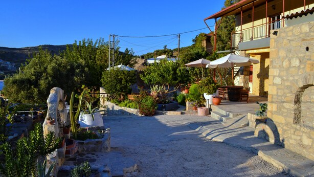 A stone building with a balcony, surrounded by potted plants and a gravel courtyard. - Villa Olive Tree (Kissamos)