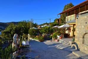 Un edificio de piedra con balcón, rodeado de macetas con plantas y un patio de grava.