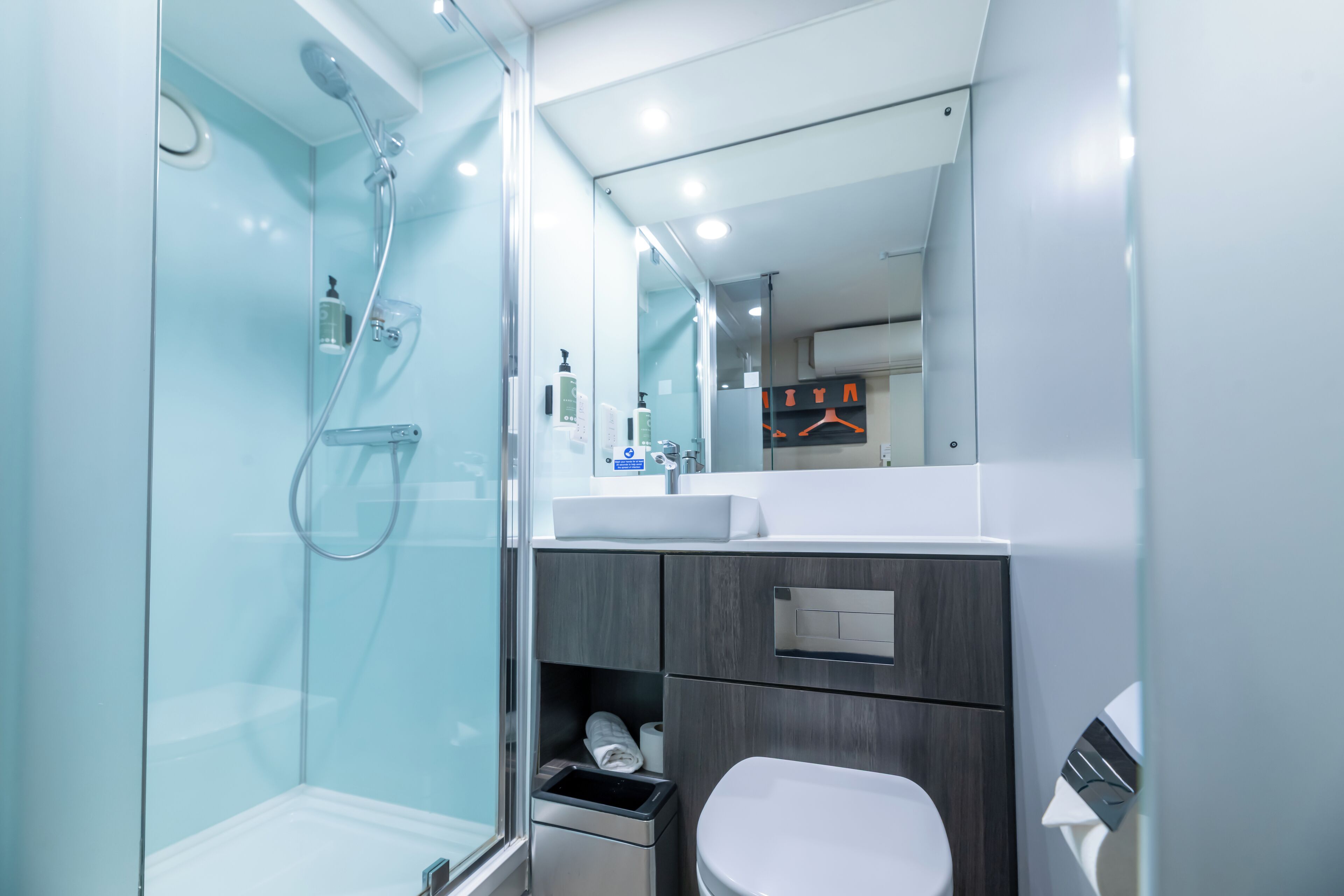 A modern bathroom with a glass shower enclosure, a white sink, and a toilet.