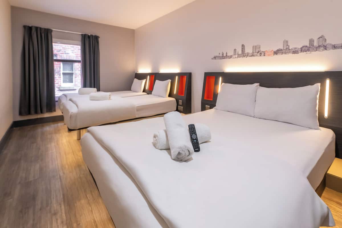 A hotel room with two beds, a cityscape mural, and a window with curtains.
