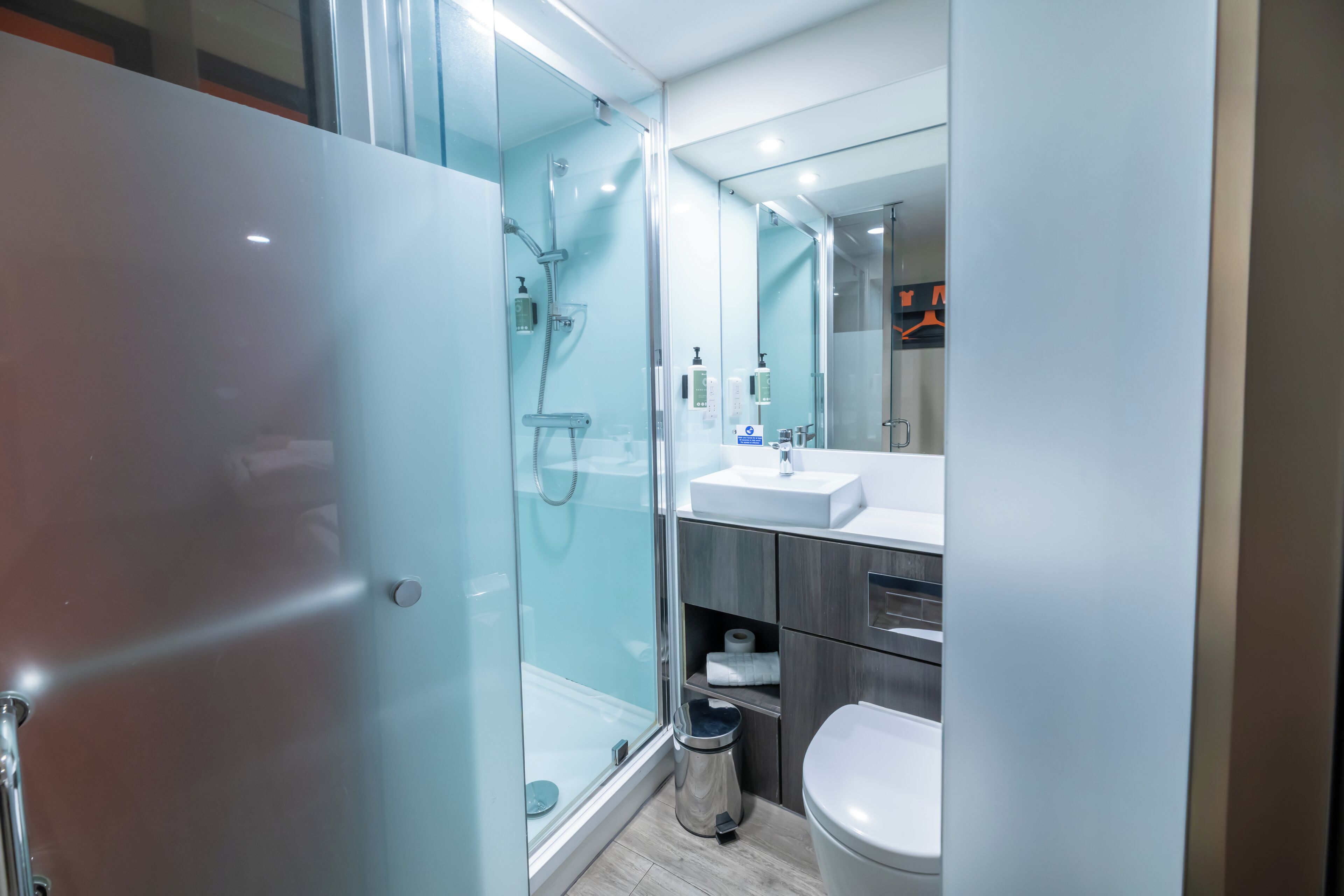 A modern bathroom with a glass shower enclosure, a white sink, and a toilet.