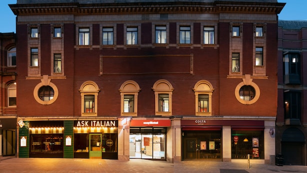 Een historisch gebouw met een koffiezaak op de begane grond en een Italiaans restaurant.