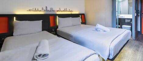 A hotel room with two beds, a cityscape wall art, and a bathroom visible through an open door.