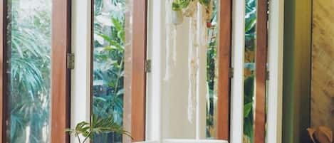 Habitación con cuna, una silla y vistas a zonas verdes a través de amplios ventanales.