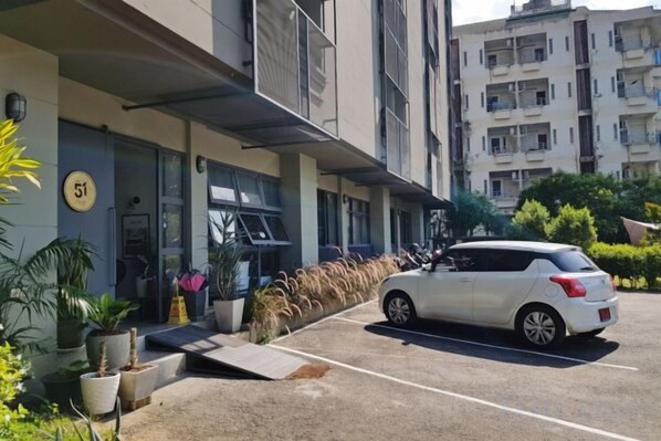 Un estacionamiento con un coche blanco estacionado frente a un edificio con un letrero con el número 51.