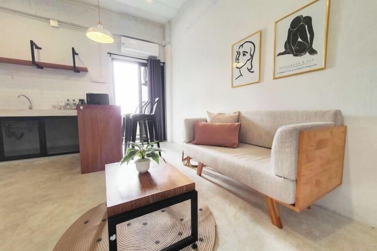 A modern living room with a sofa, a coffee table, and a dining area with chairs.