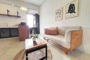 A modern living room with a sofa, a coffee table, and a dining area with chairs. - The51Hometel (Chiangmai)