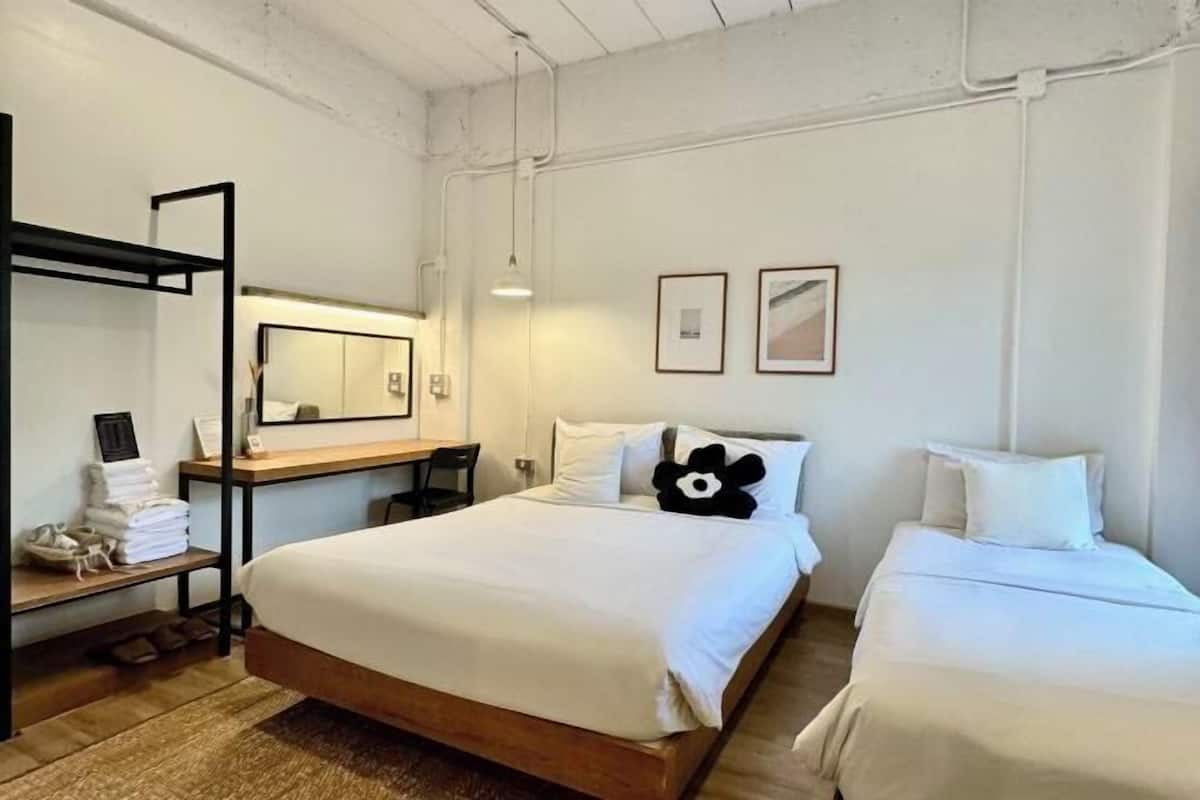 Une chambre d’hôtel avec un grand lit, un bureau avec une chaise, un miroir et deux tables de chevet avec des serviettes.