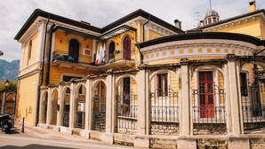 A yellow building with arched windows and a balcony. - Arciduca Charming House (Arco)