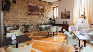 A dining area with tables and chairs, a stone wall, and a painting. - Arciduca Charming House (Arco)