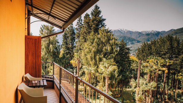 A balcony with a view of a mountainous landscape, a wooden door, and two chairs. - Arciduca Charming House (Arco)
