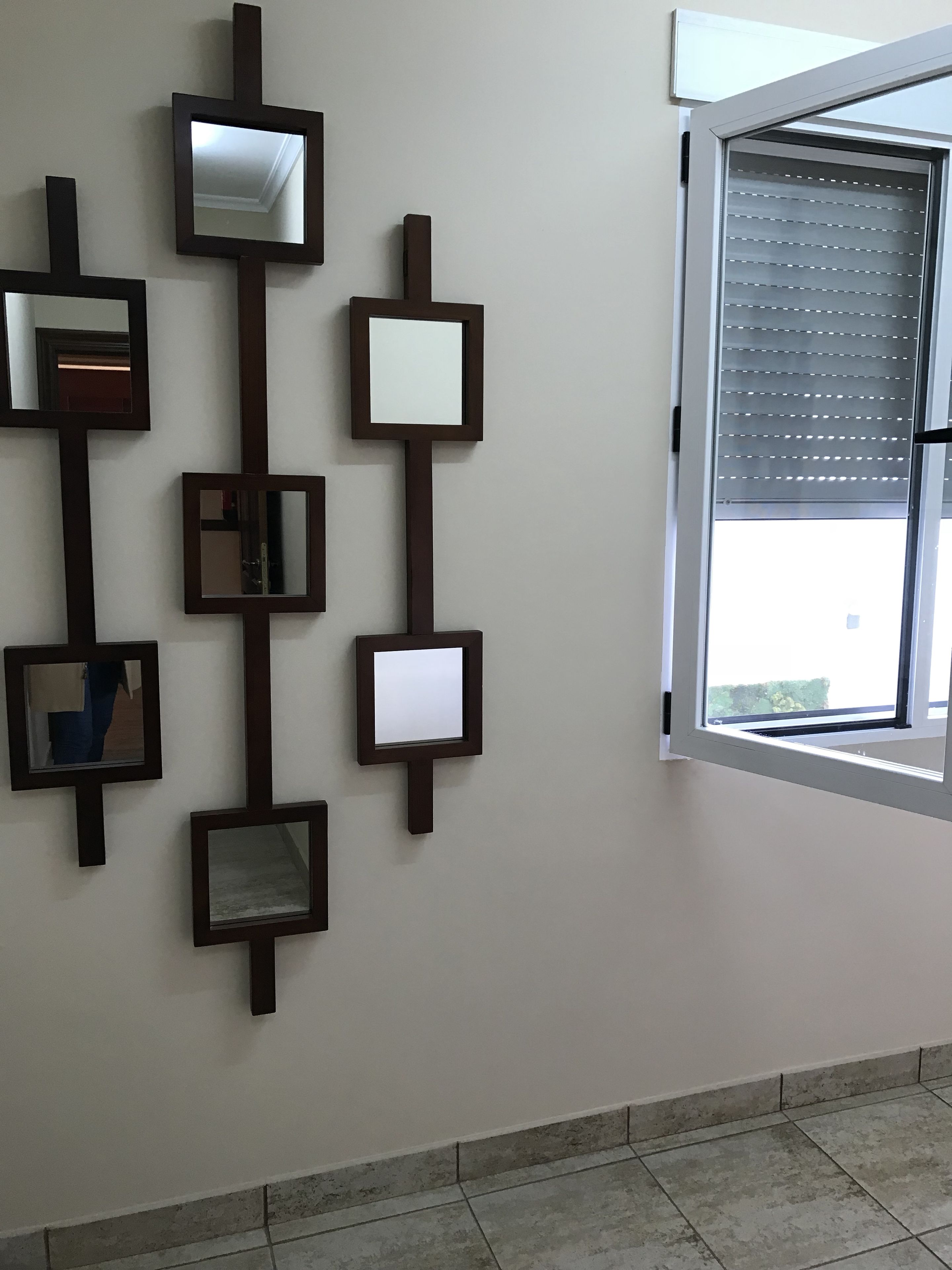 A wall with multiple rectangular mirrors of varying sizes arranged vertically.