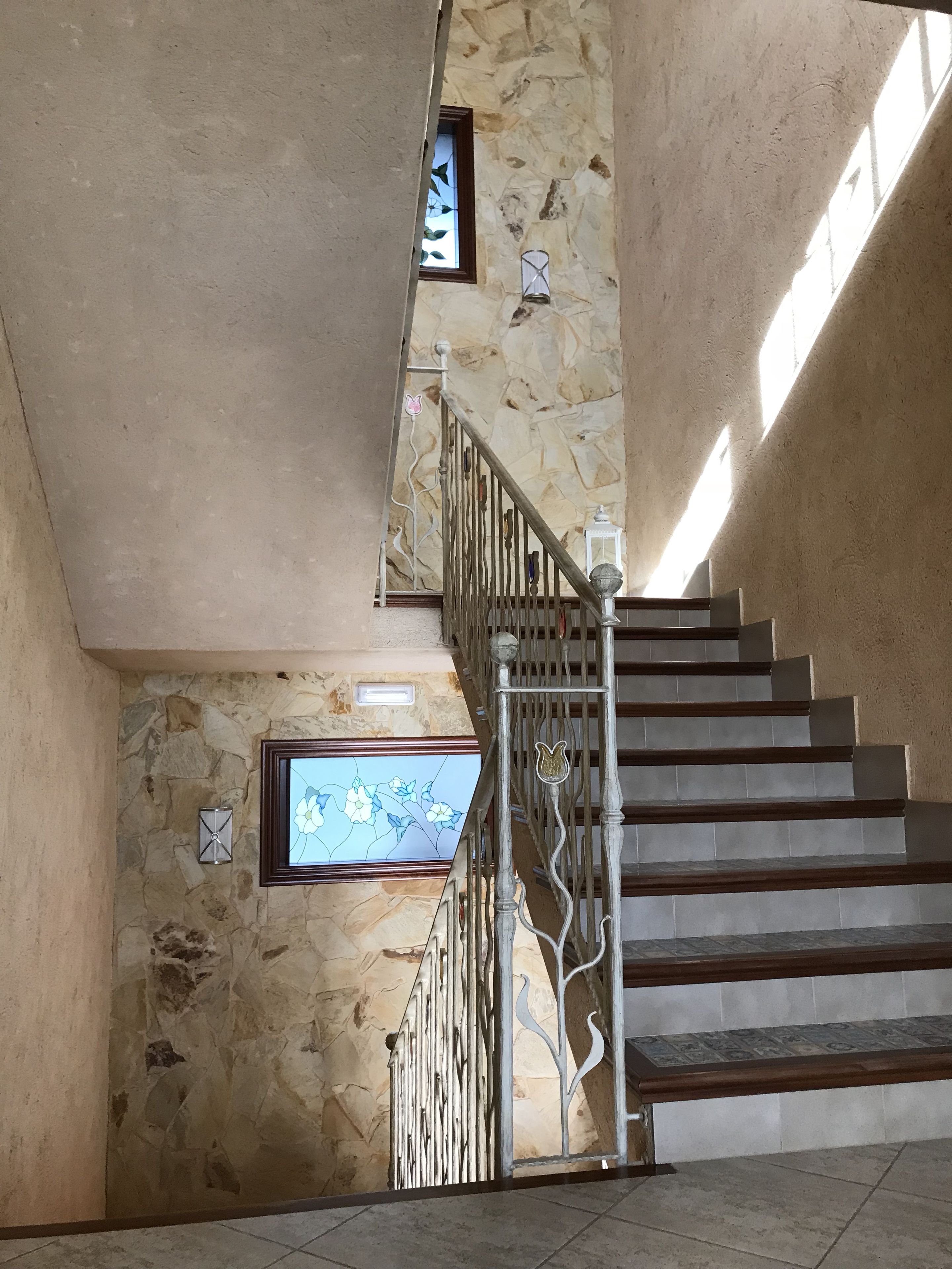 Una escalera con un muro de piedra y una ventana de vitral.
