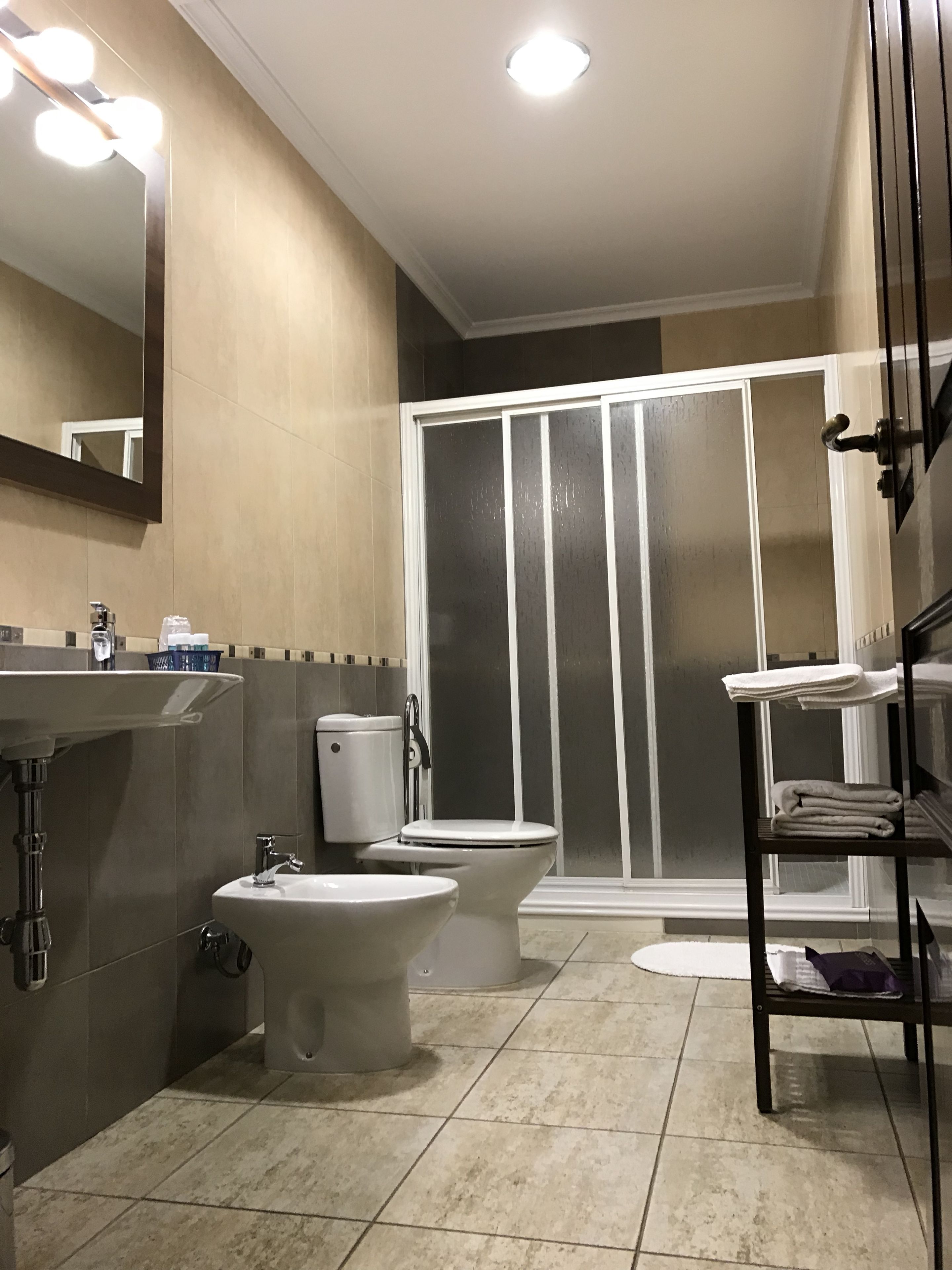 Un baño con inodoro, bidé, lavamanos y zona de ducha.