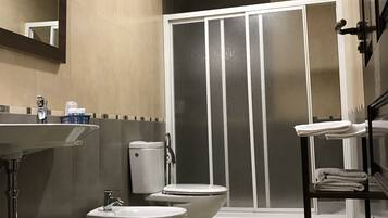 Un baño con inodoro, bidé, lavamanos y zona de ducha.