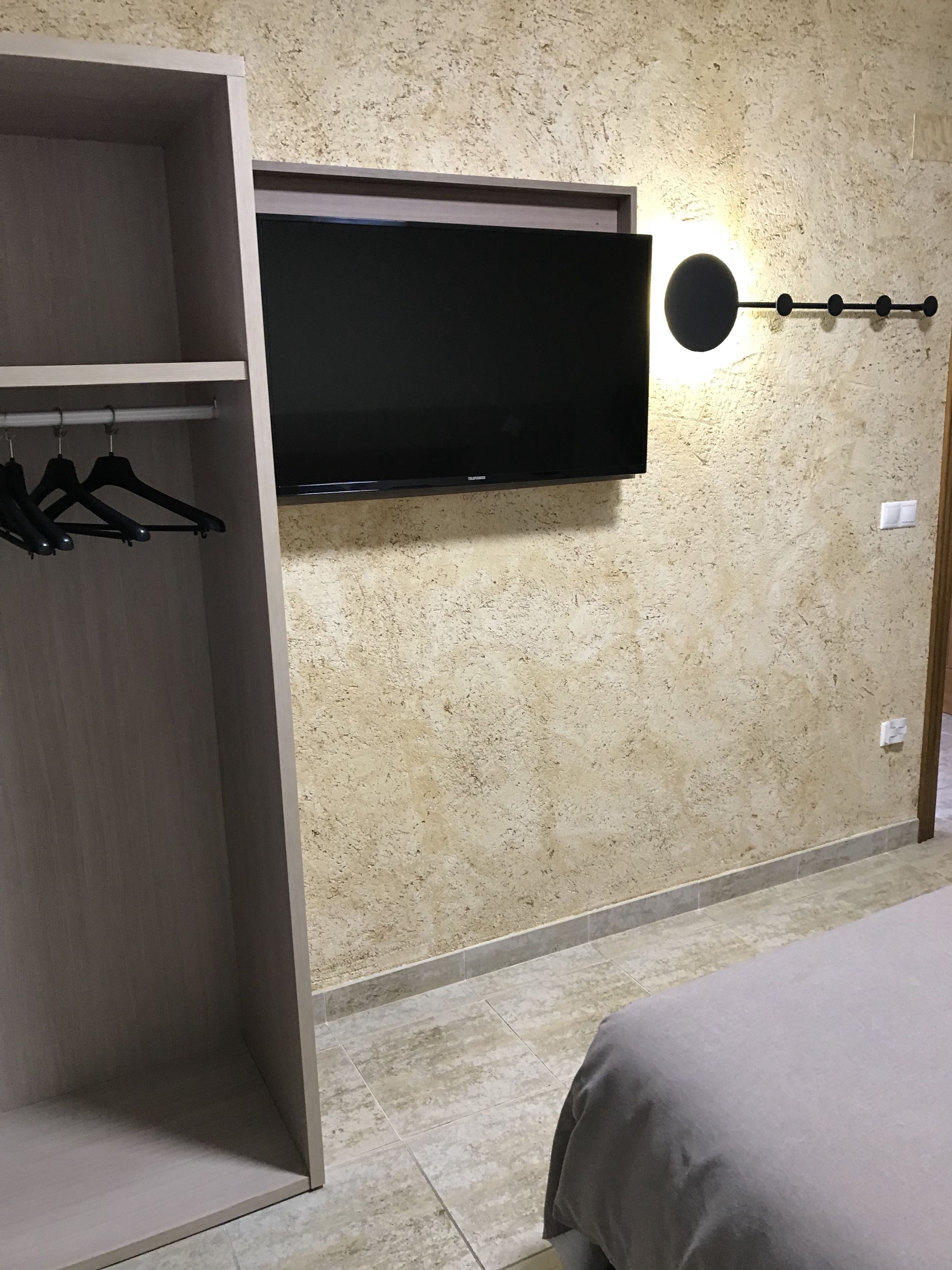 A room with a wardrobe, a bed, and a wall-mounted TV.