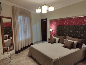 A hotel room with a large bed, a mirror, a nightstand with a lamp, and a red patterned headboard. - Hostal Rural Los Girasoles de iniesta (Iniesta)