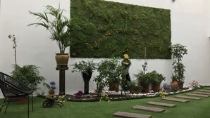 A garden area with a variety of potted plants, a decorative wall with greenery, and a wooden pathway.