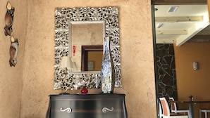 A room with a dark wooden dresser, a mirror with an ornate frame, and a decorative vase.
