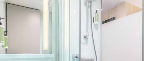 Une salle de bain moderne avec une douche à parois de verre, un distributeur de savon à portée de main et un miroir.