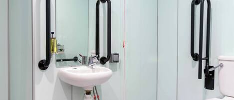 A modern bathroom with a white sink, a mirror, and a toilet.