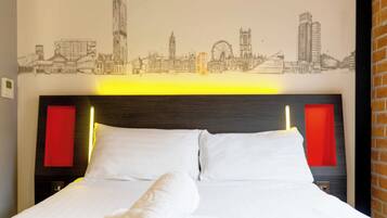 A hotel room with a bed, a cityscape mural on the wall, and red accent lighting.