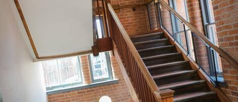 Una escalera con barandillas de madera y paredes de ladrillo, que conduce a un piso superior.