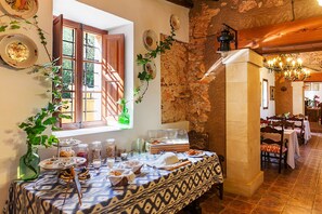 A dining area with a buffet setup, stone walls, and wooden furniture. - Agroturísme Ca'n Gaià (Felanitx)