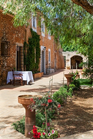 A courtyard with a table and chairs, a stone wall, and a flower pot.