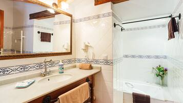 Un baño con lavamanos, espejo y bañera.